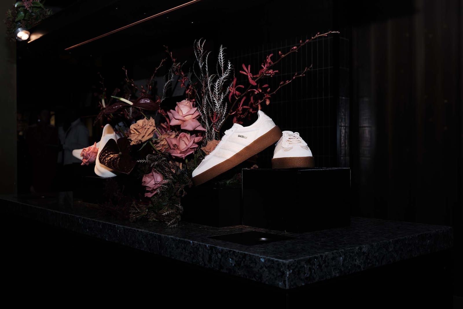Trainers on a stone plinth among dark flowers