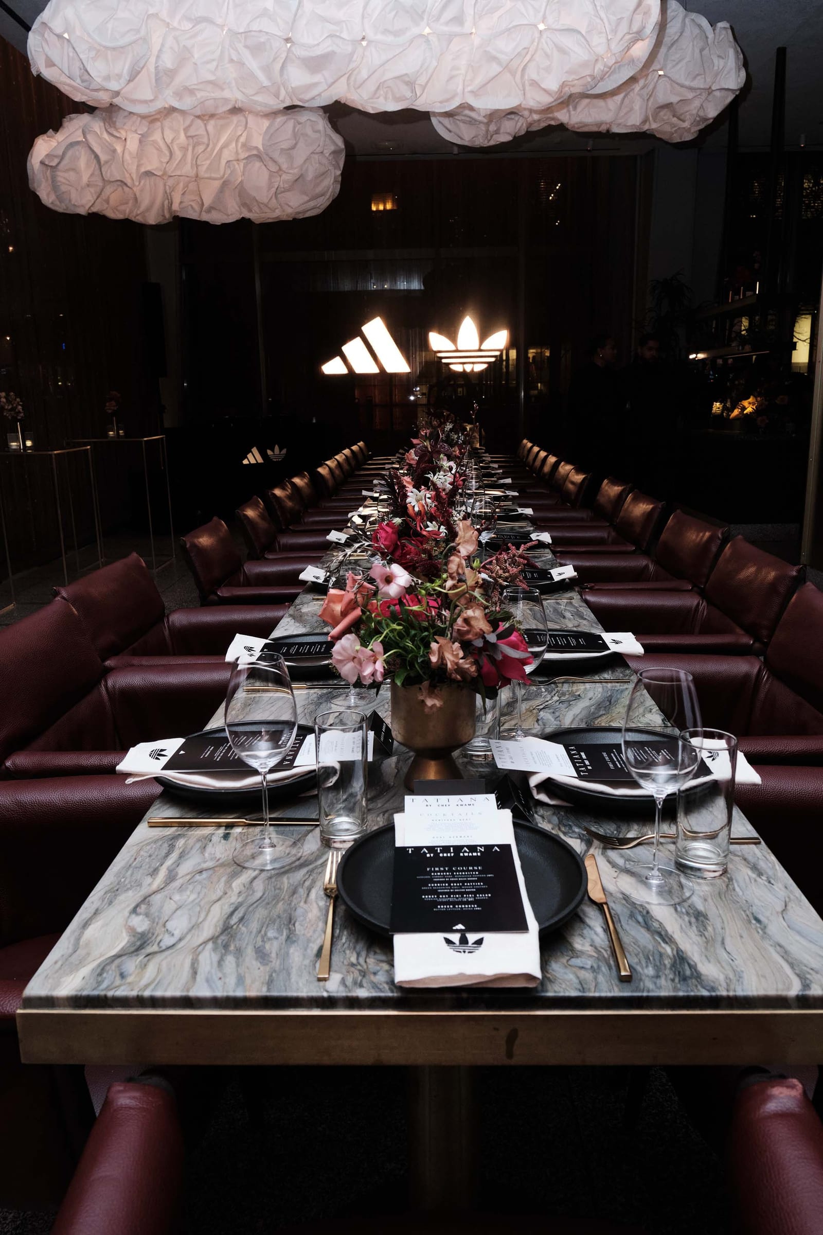 A long dinner table set under paper lanterns