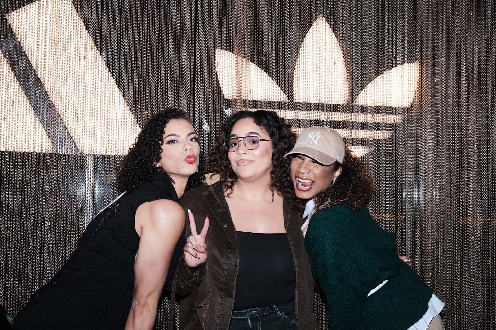 Three guests posing against the lit wall