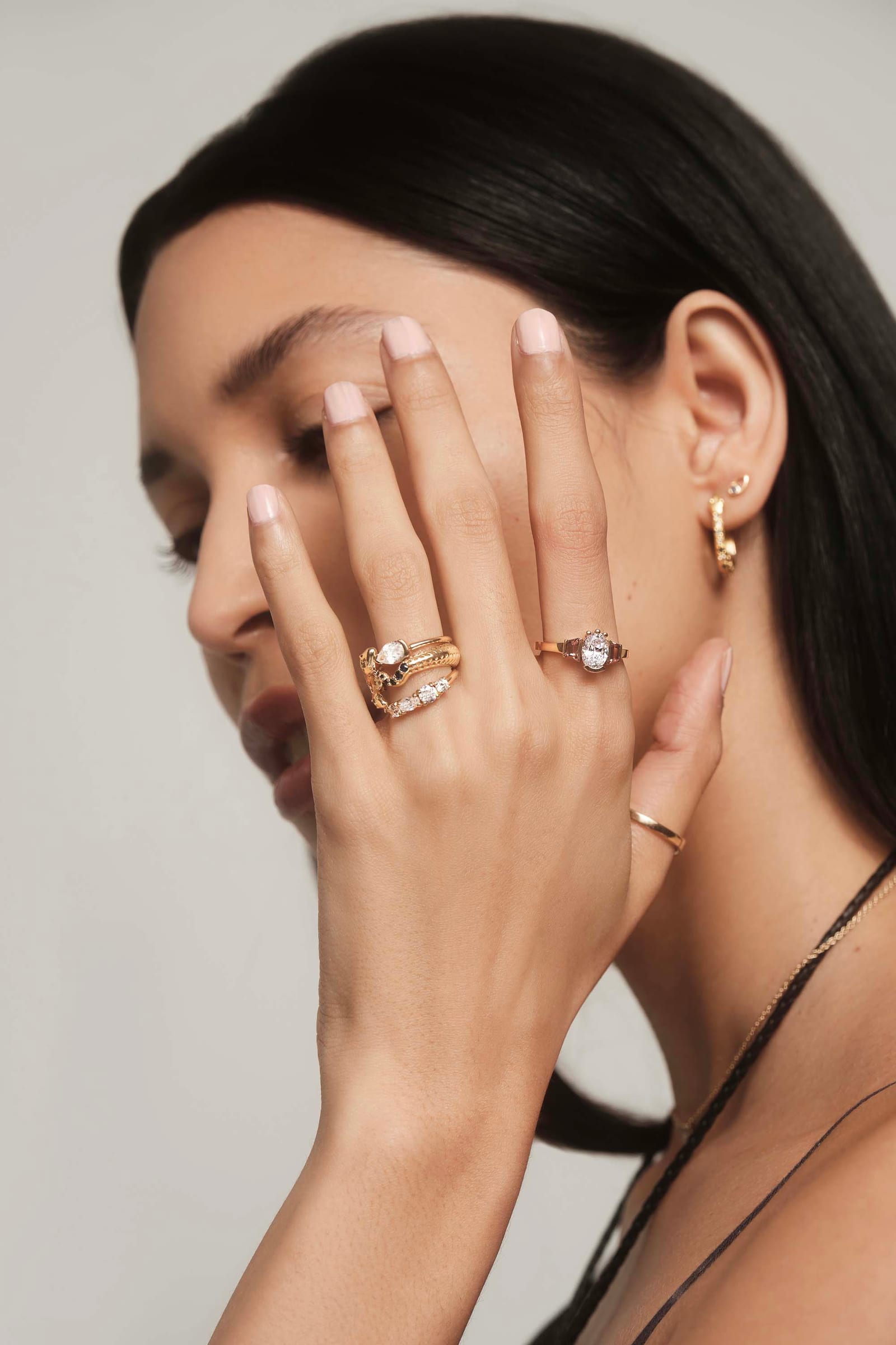 Rings worn across a hand held to the face