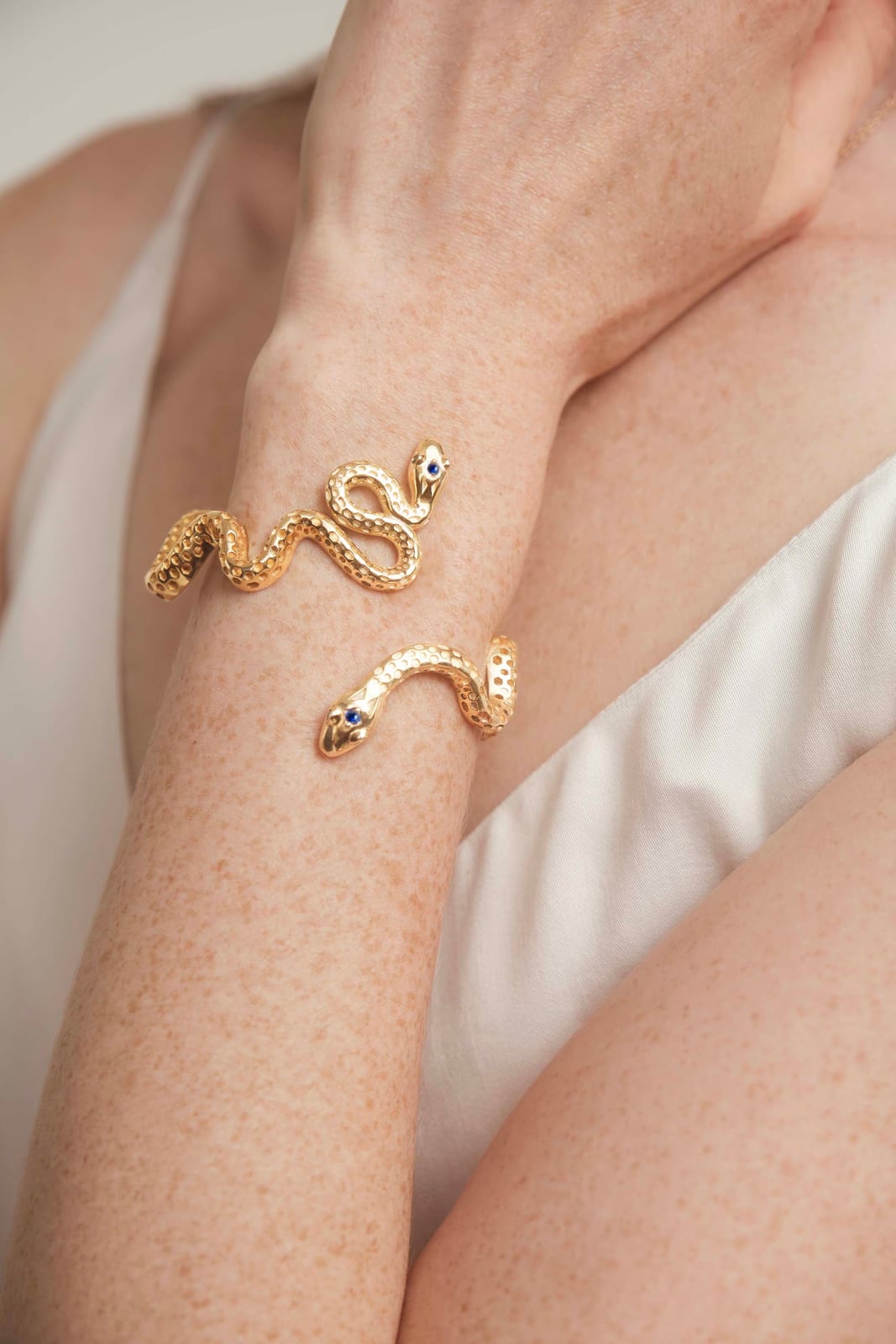 A gold snake cuff on a bare arm