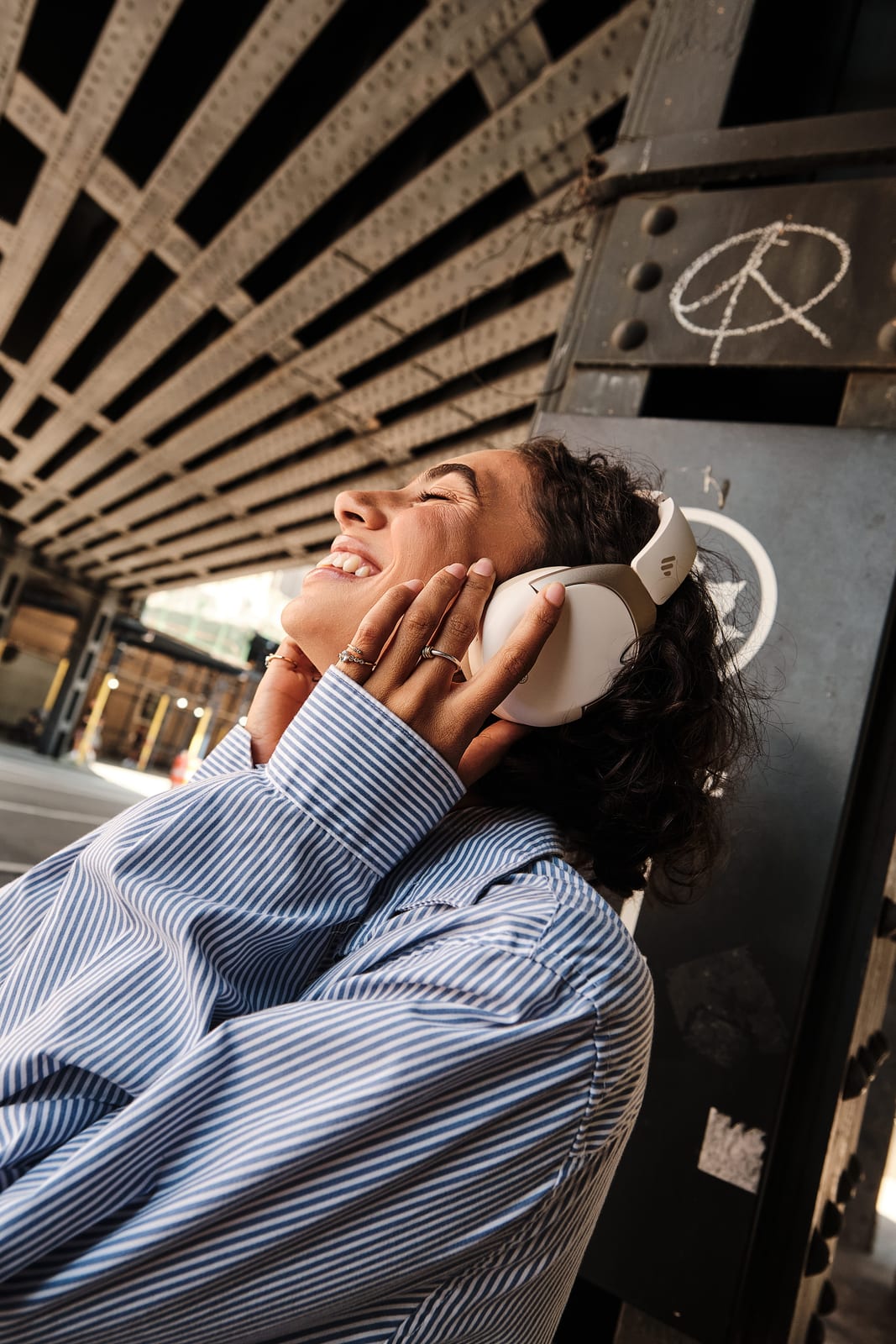 A commuter smiling under an elevated railway