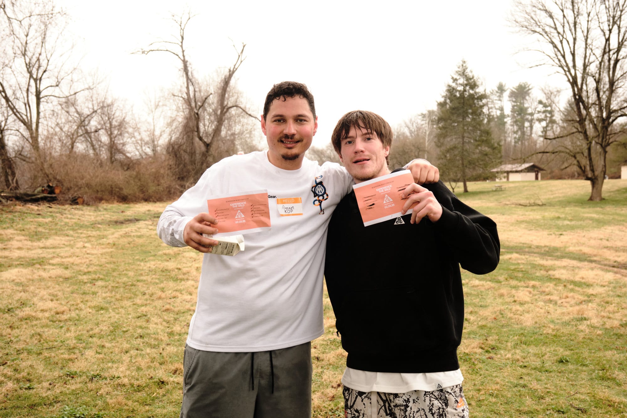 Two members of the Ekin crew holding cards in a winter park