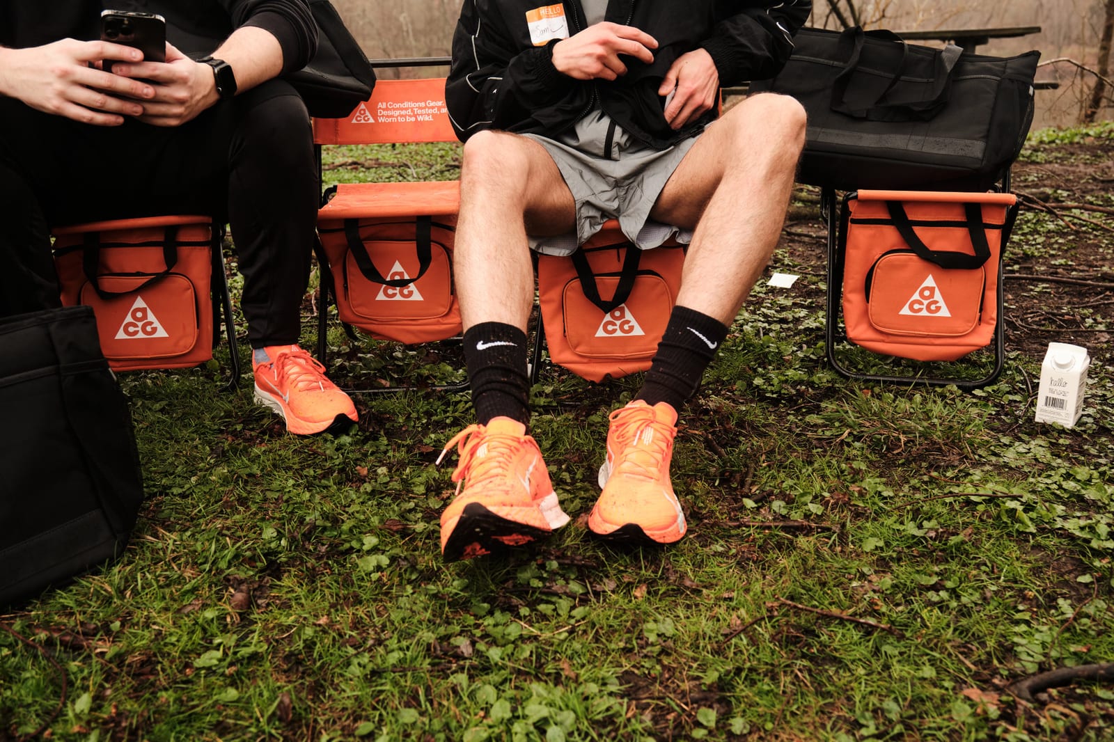 Orange sneakers and kit bags on wet grass