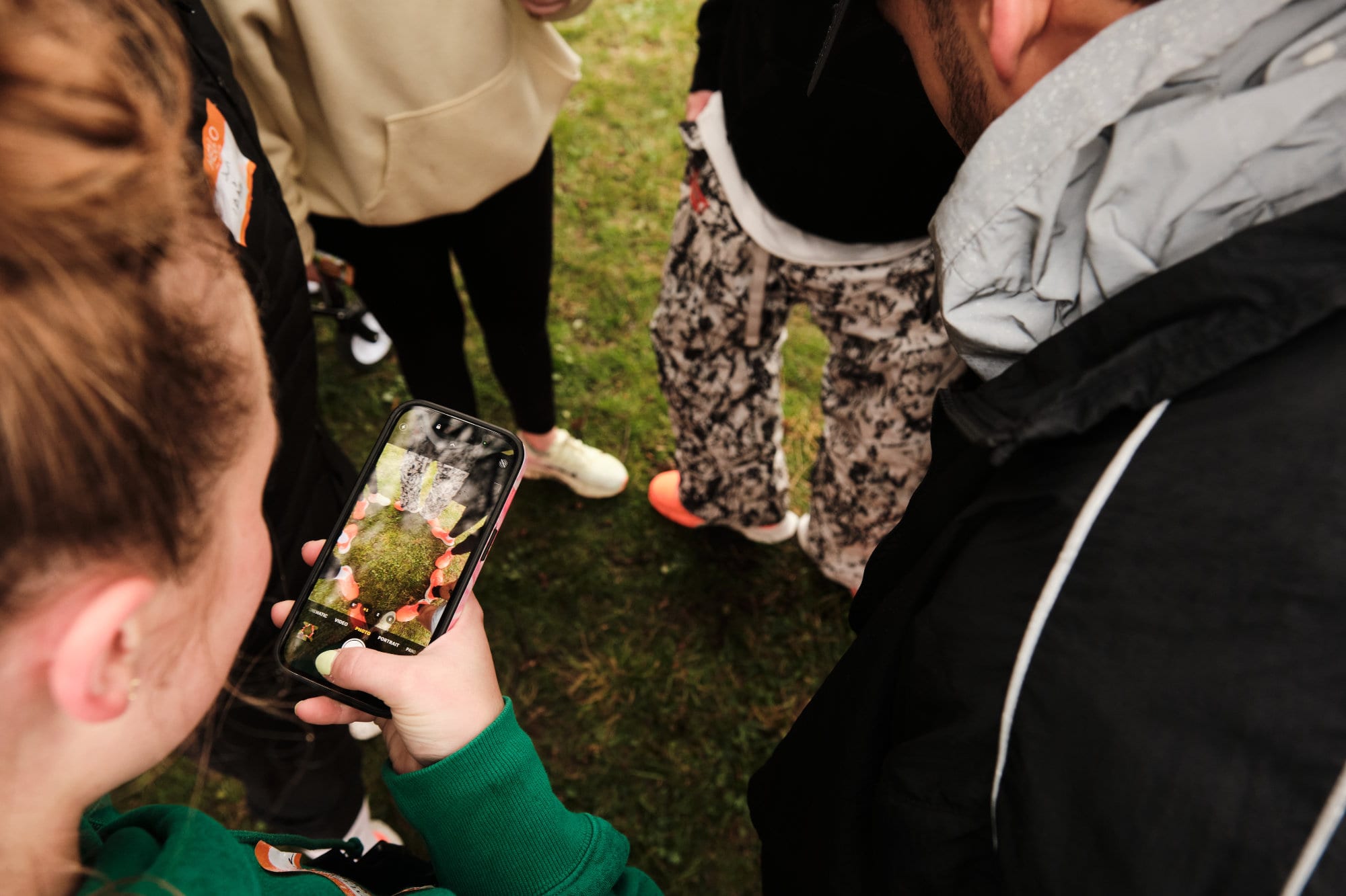 A phone held up to photograph sneakers on the grass