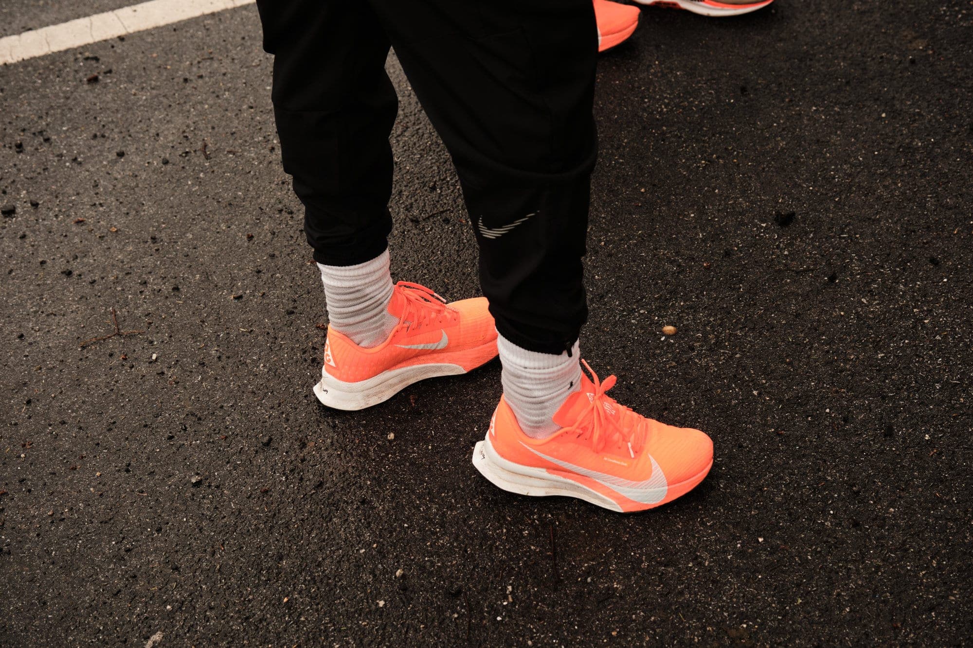 Orange running shoes on wet asphalt