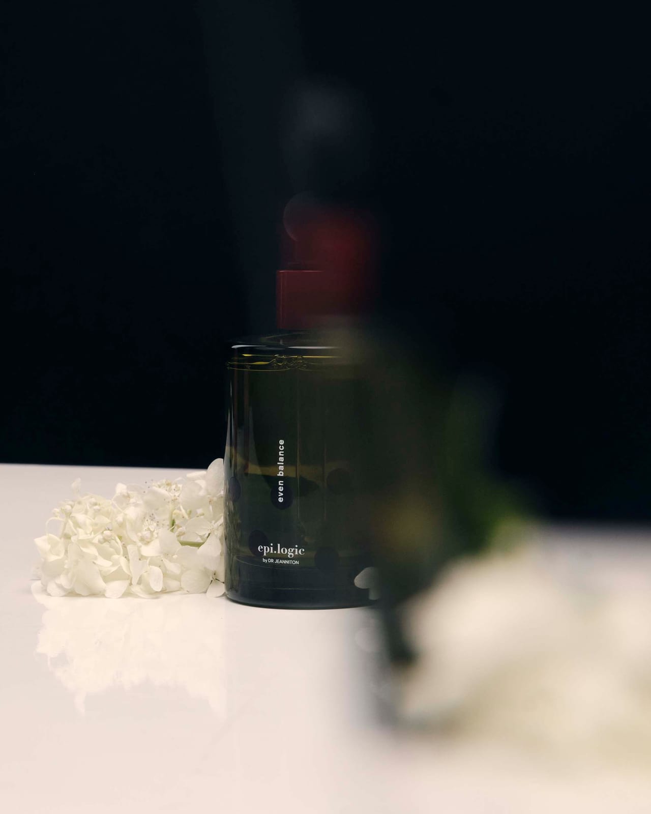 A dark bottle behind falling petals