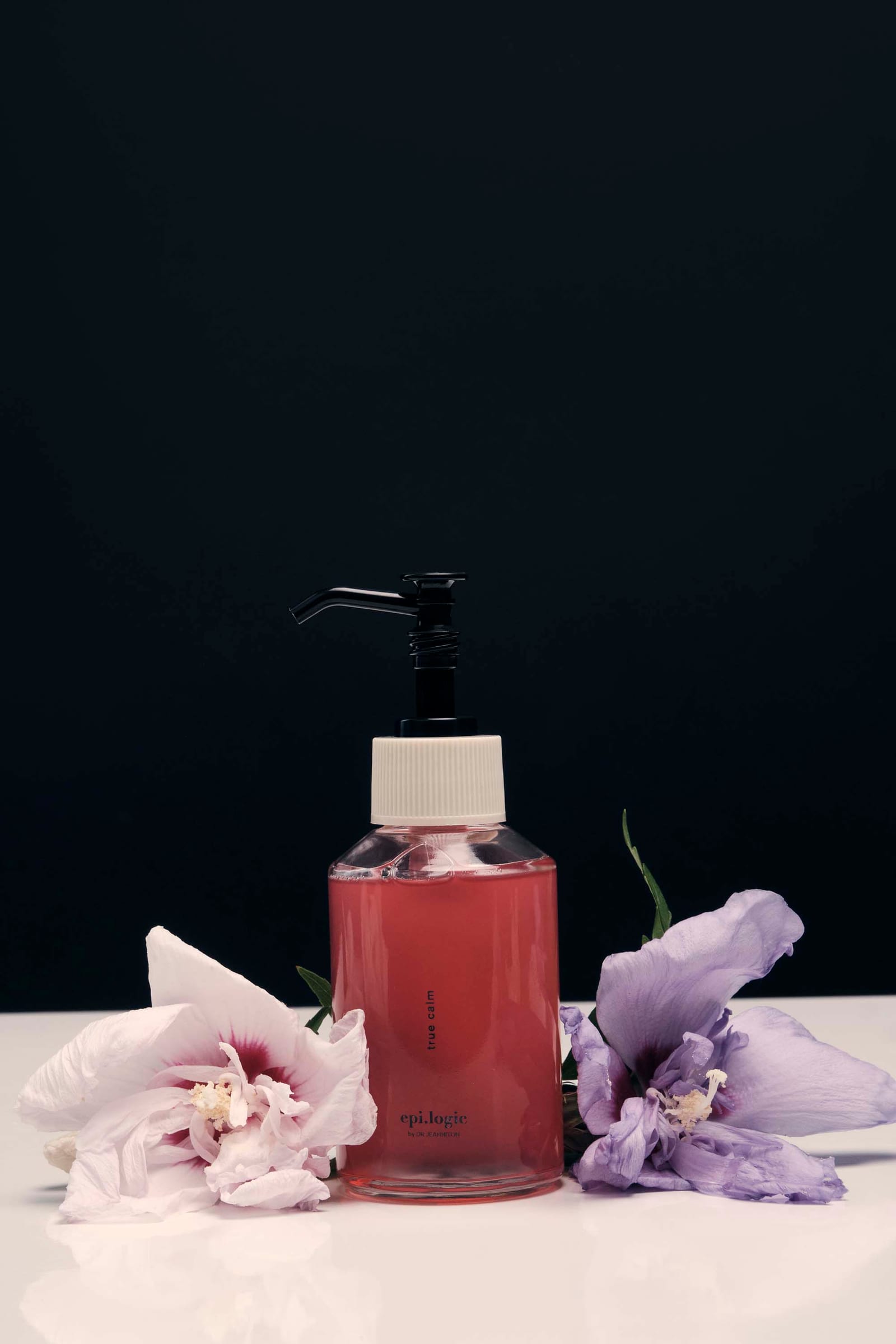 A pink bottle between two spent blooms