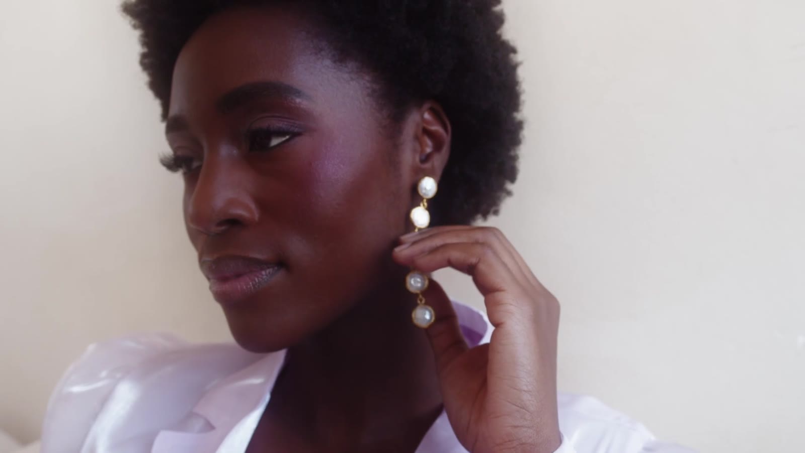 A white blazer and a pearl earring in window light