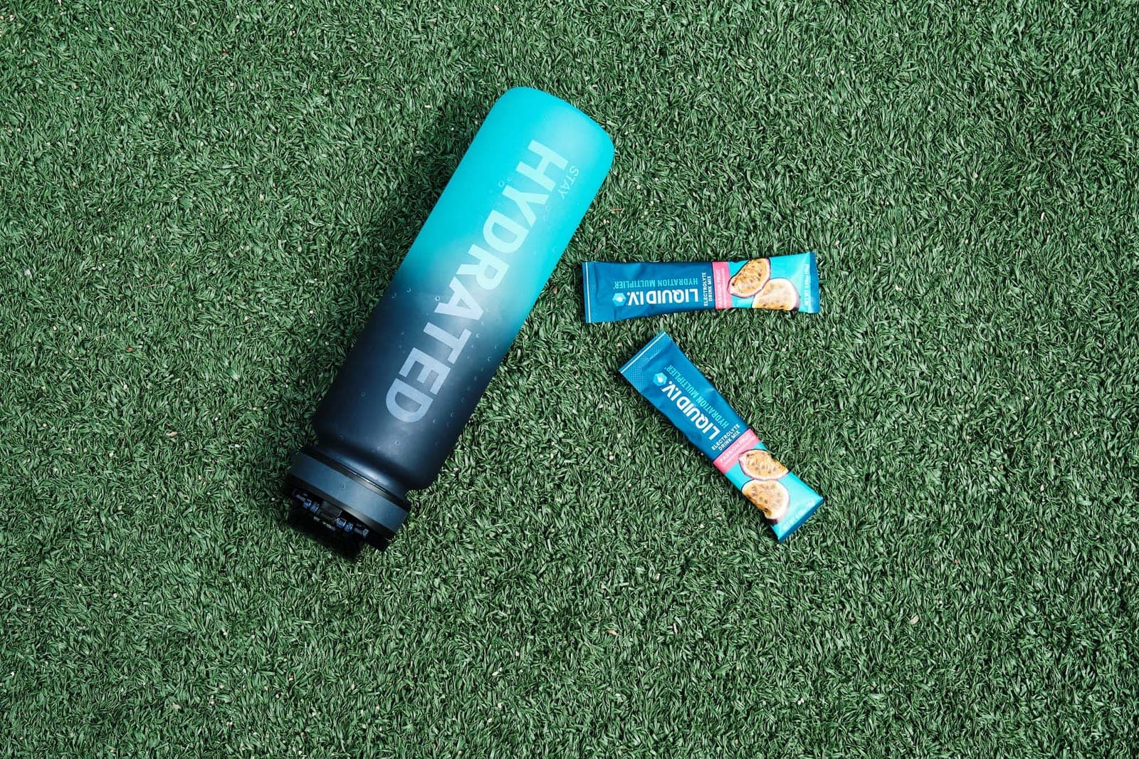 A bottle and two sachets laid out on turf