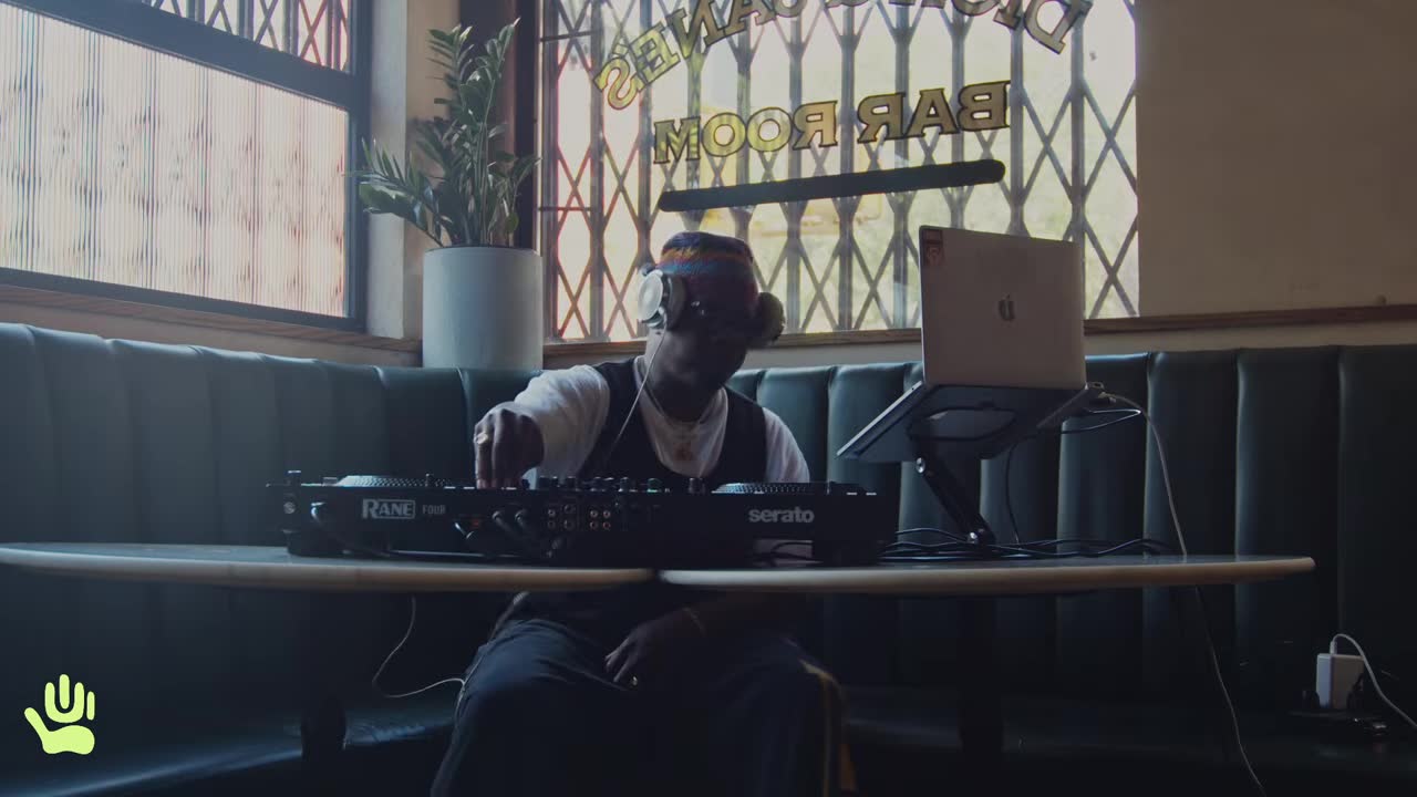 A DJ at the decks in a green booth, from The Connection Radio