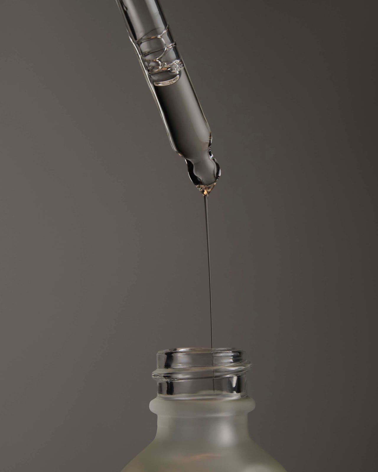 A dropper suspended over an open bottle