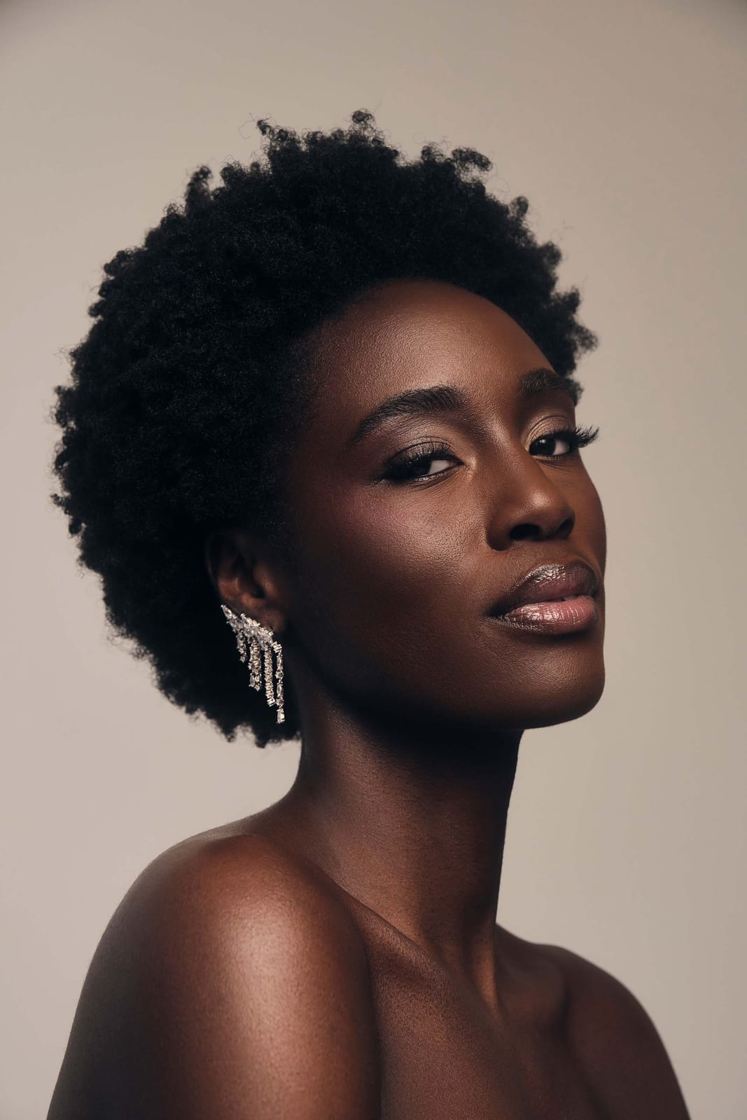 A bare shoulder turned into the light, earrings catching
