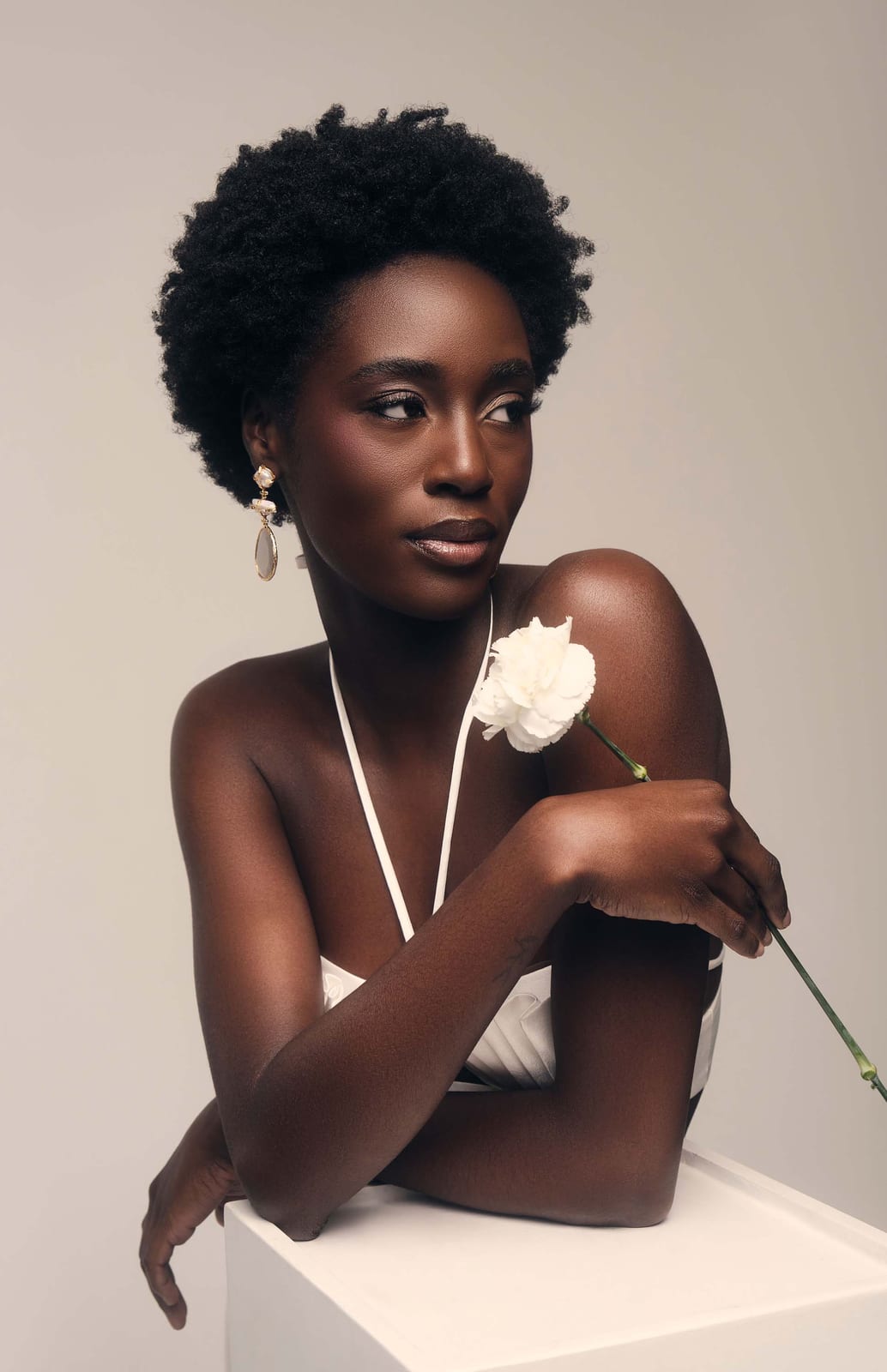 Seated with a white rose against a pale wall